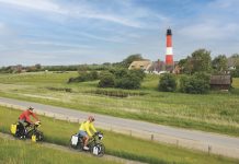 Nordseeküsten-Radweg: Zwischen Dünen und Deich Radfahrer vor dem Leuchtturm der Insel Pellworm, Nordfriesland, Nordsee, Schleswig-Holstein, Deutschland